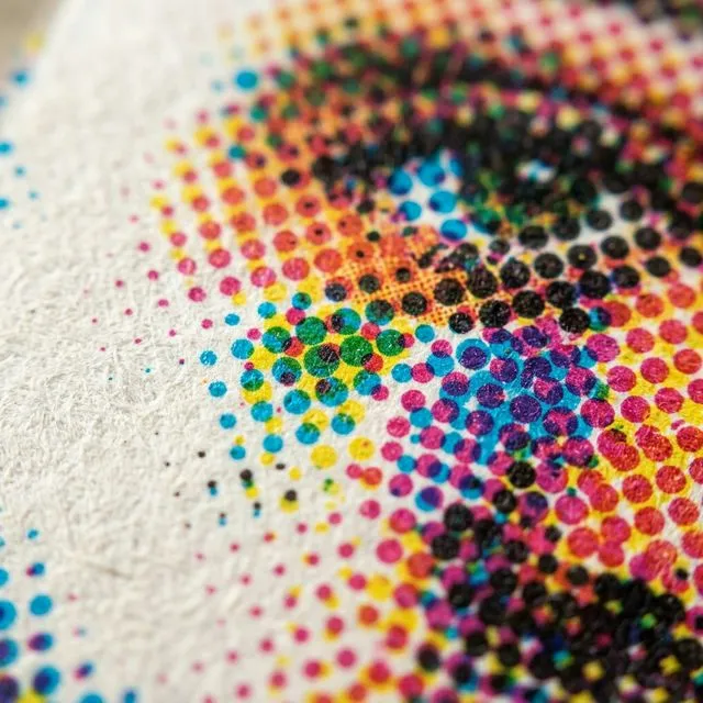 Extreme macro of CMYK halftone dots on printed paper showing cyan, magenta, yellow and black ink dots