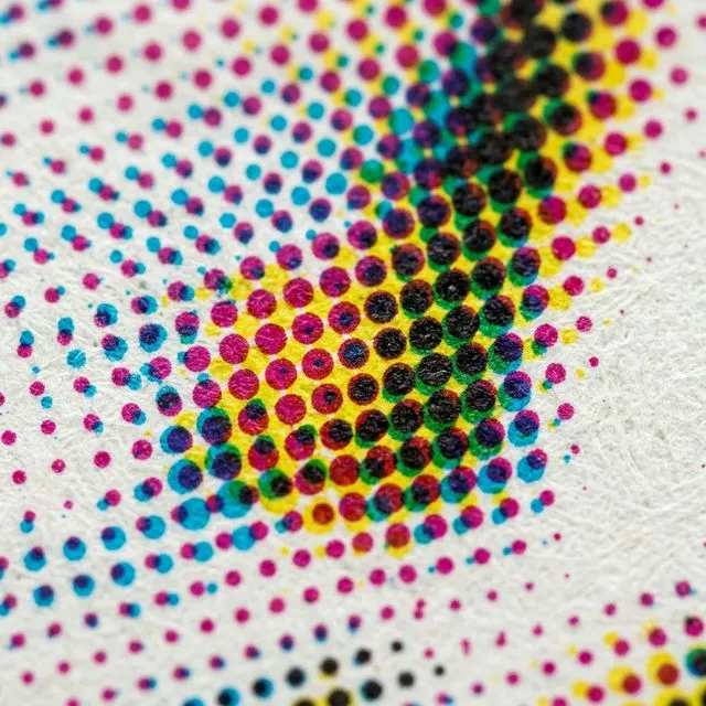 Macro photograph of CMYK halftone dots forming a color image on paper